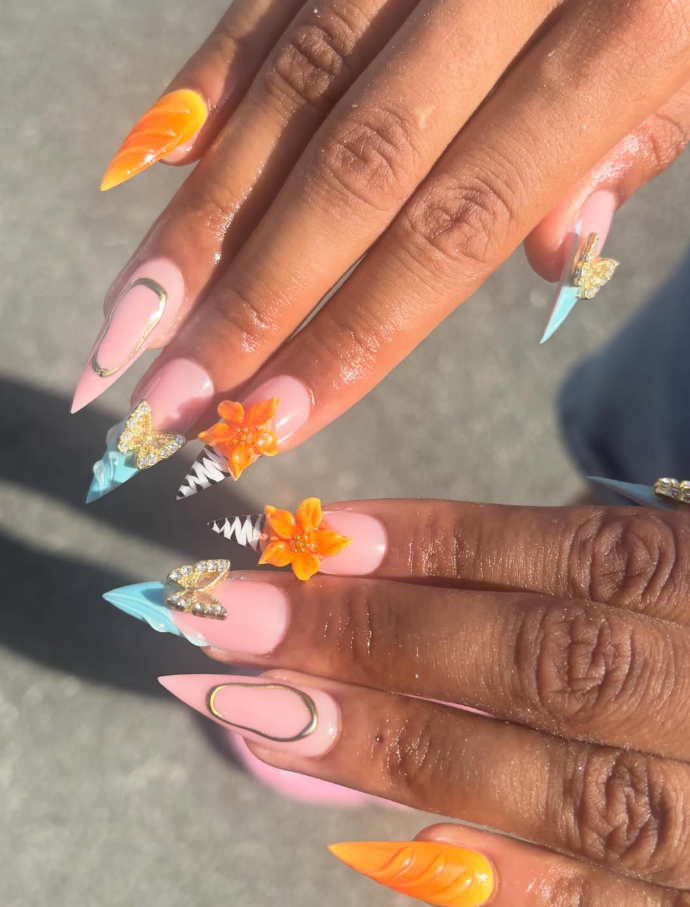 Ongles colorés avec fleurs et bijoux dorés